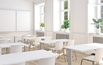 A class room filled with white chairs and white tables.